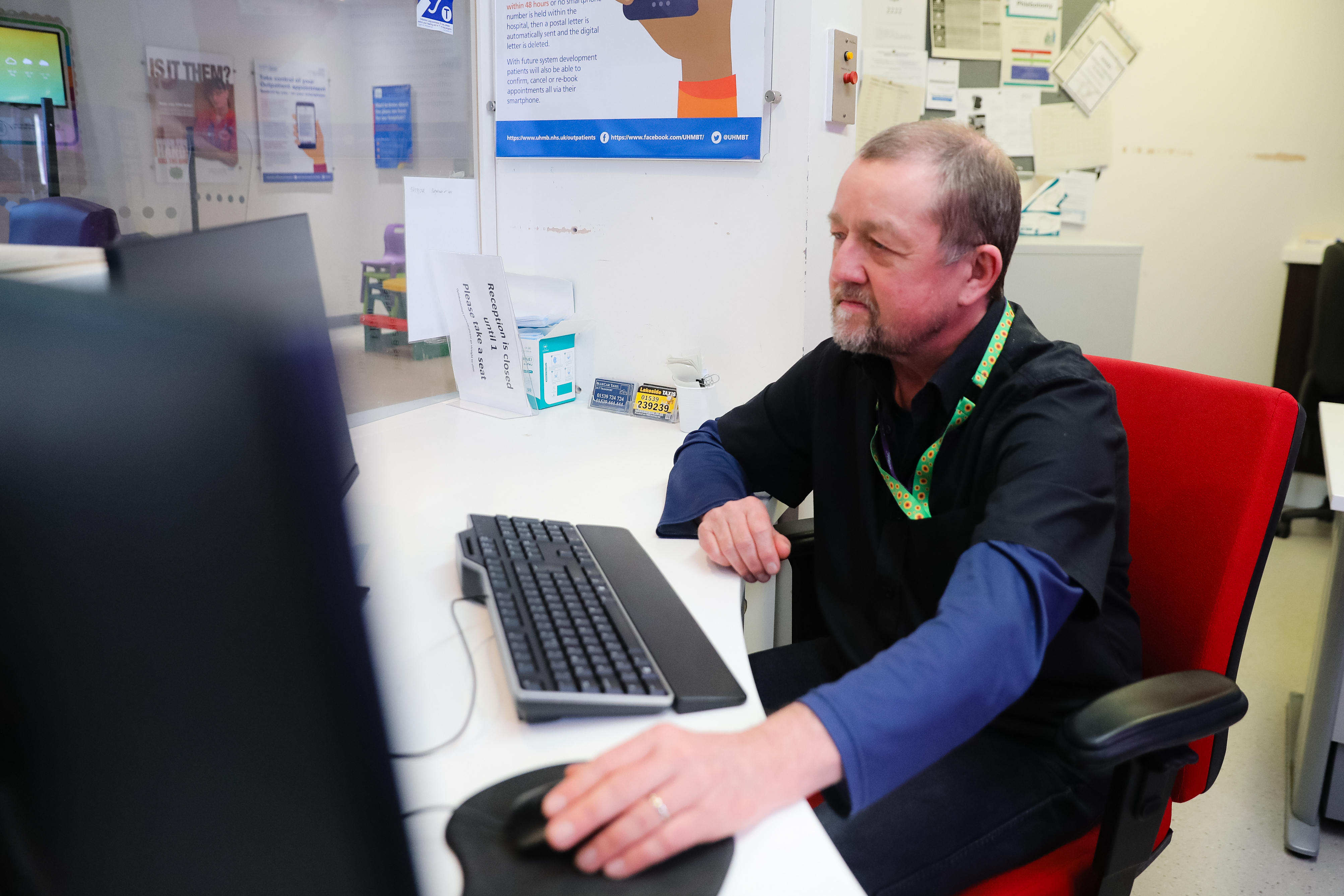 A Morecambe Bay NHS colleague sat at a desk working on a computer