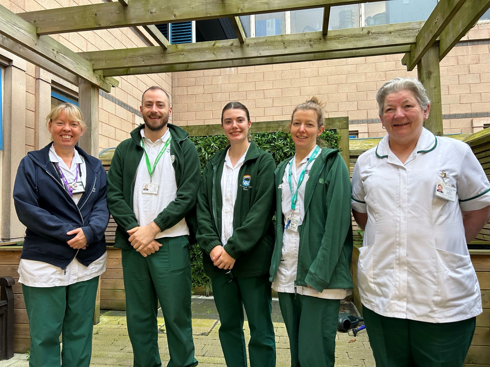 Group photo of 5 stroke service colleagues standing outside and smiling to camera