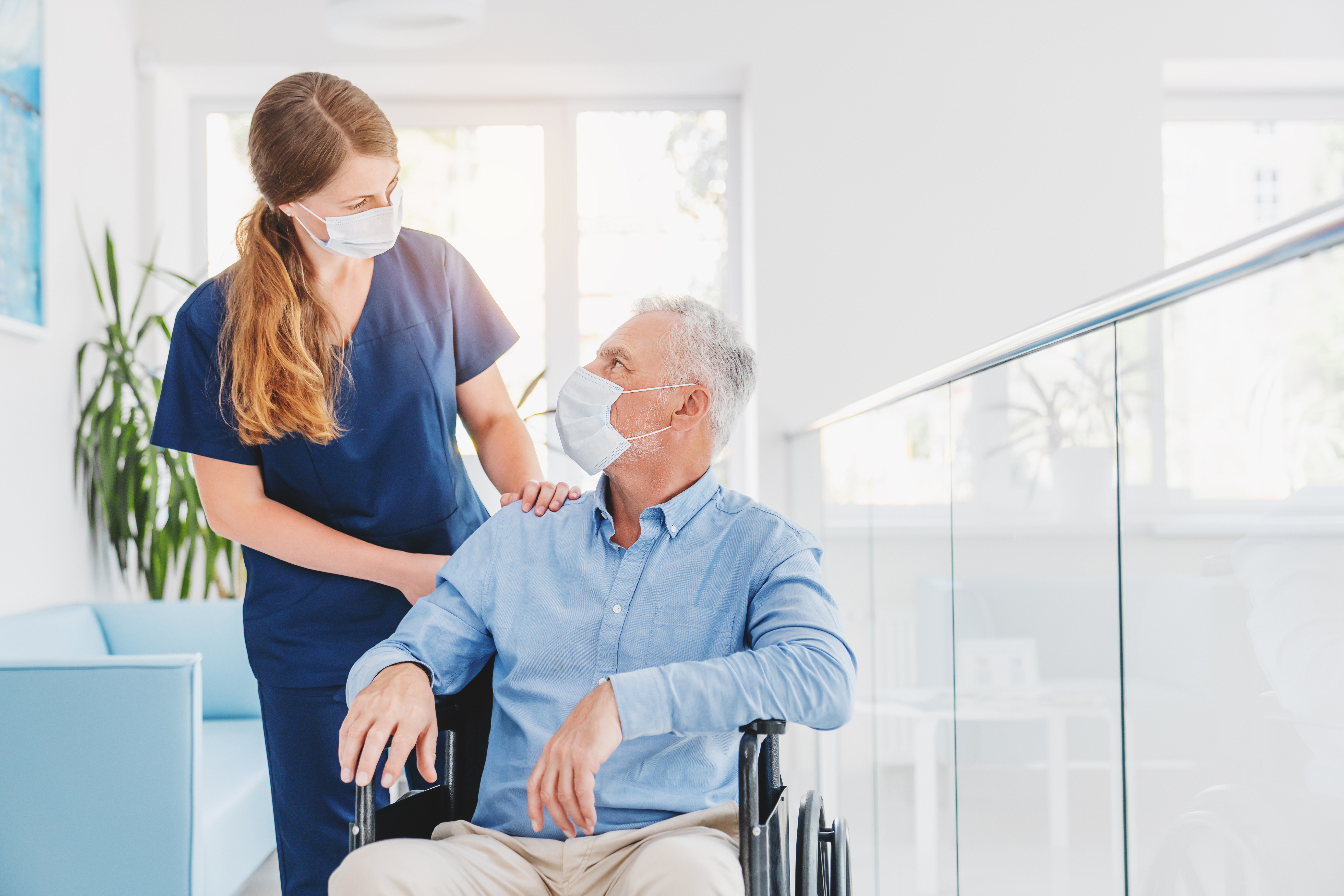 Stock image of a nurse helping an older gentlman in a wheelchair