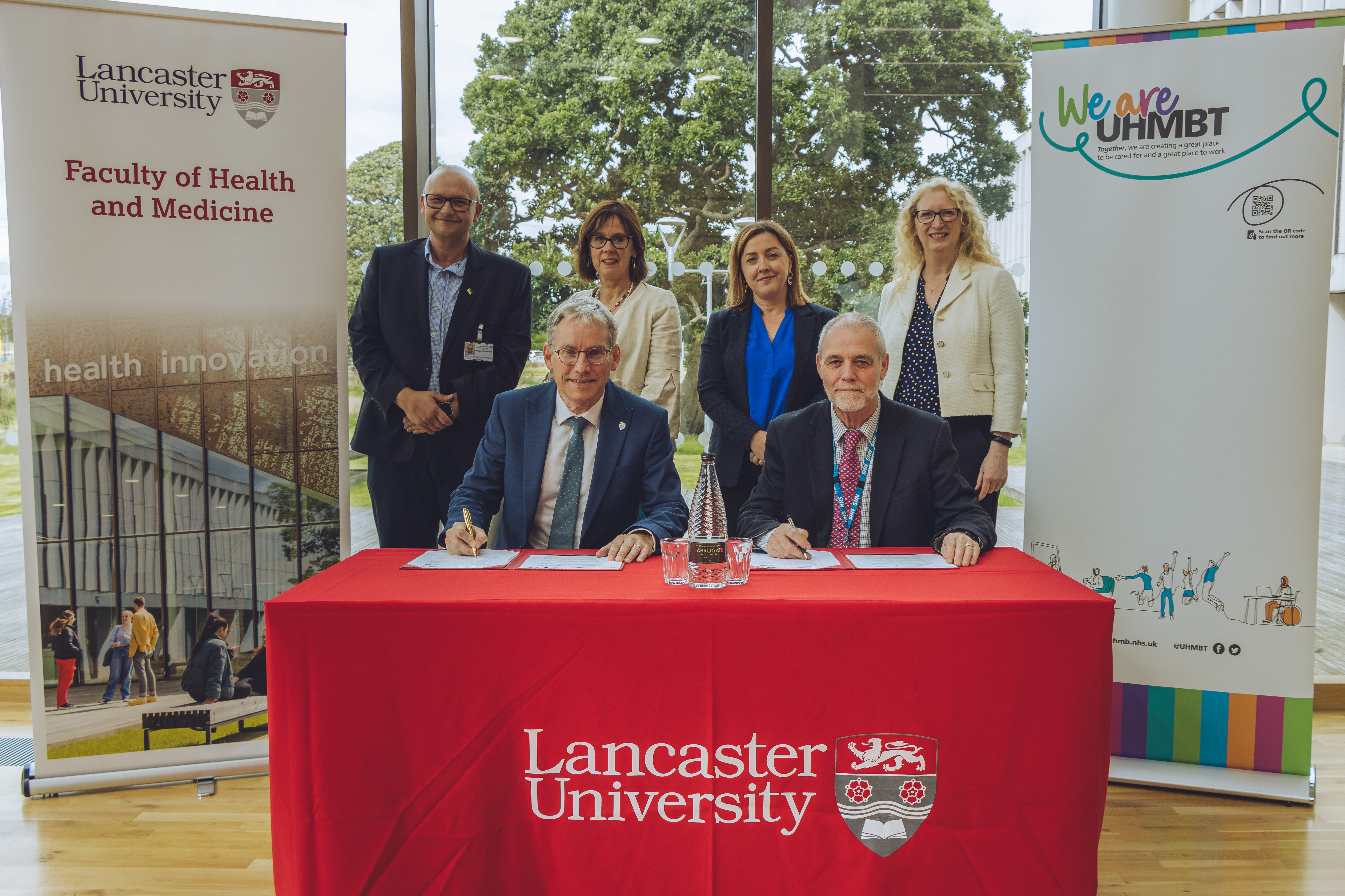 Professor Andy Schofield and Professor Mike Thomas signing the Memorandum of Understanding with Phil Woodford and Lancaster University Executive Dean for Health and Medicine Professor Jo Rycroft-Malone OBE, Head of Partnerships for Health and Social Care Laura Kornas and Head of Stakeholder Relations and Non-Executive Director for UHMBT Sarah Rees